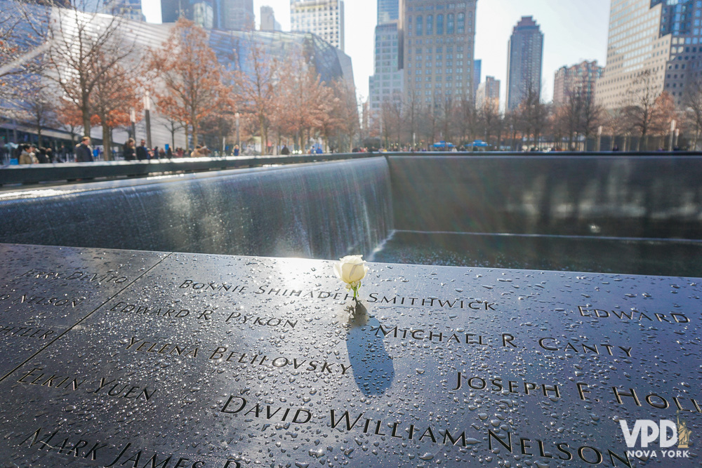 Foto de uma flor em cima de uma das placas com o nome das vítimas no Memorial do 11 de Setembro, em Nova York