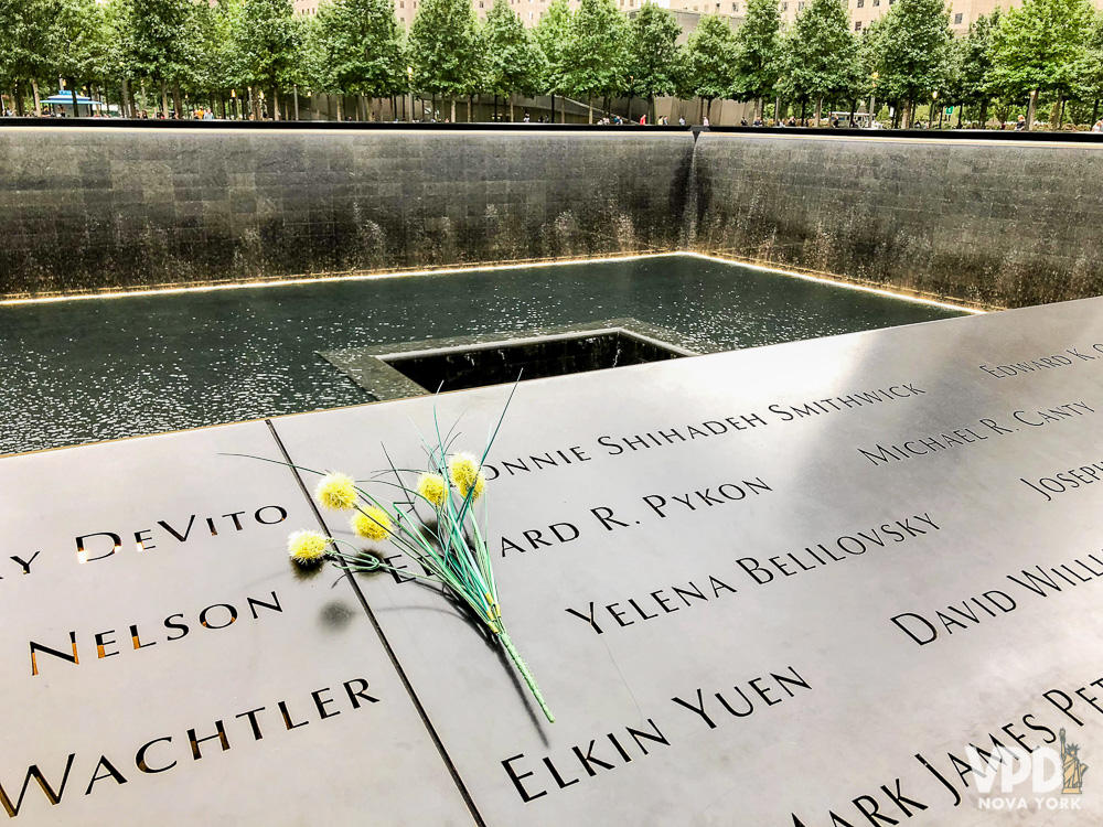 Foto de uma flor sobre uma das placas homenageando as vítimas no Memorial do 11 de Setembro em Nova York