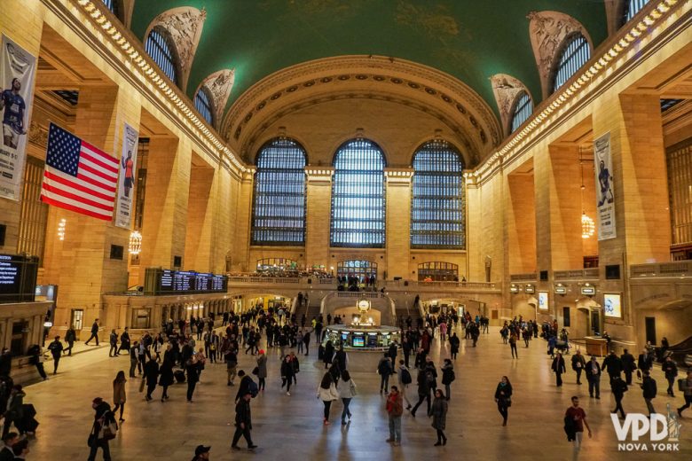 Foto do interior da estação Grand Central, em Nova York, com a cúpula alta pintada de verde e visitantes circulando 