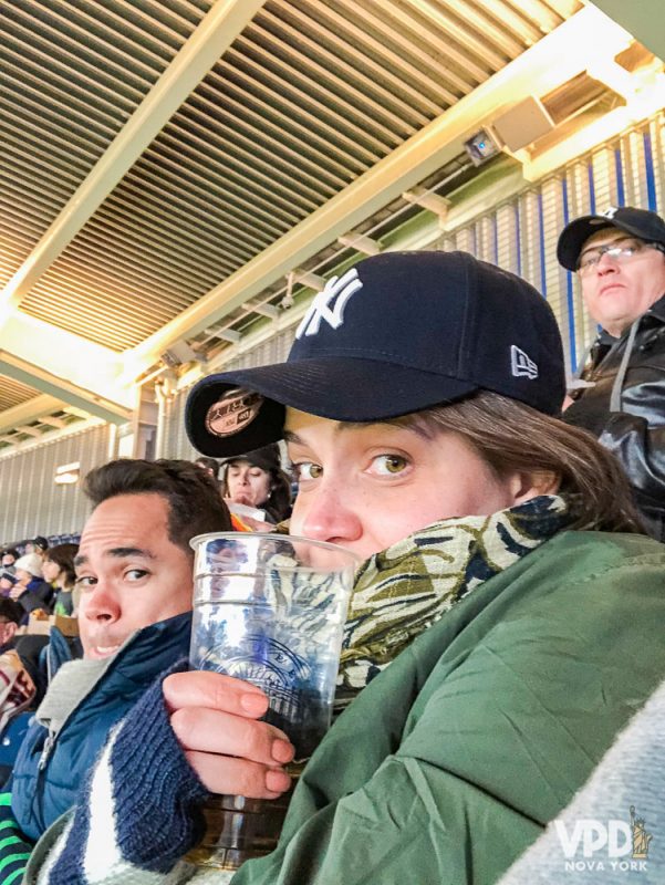 Foto da Bia passando frio e cheia de casacos no jogo de baseball.