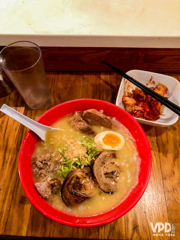 Foto da tigela de ramen do Totto Ramen, em Nova York, com a entrada de kimchi ao lado 