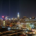 Foto da cidade de Nova York iluminada à noite, com o céu escuro ao fundo