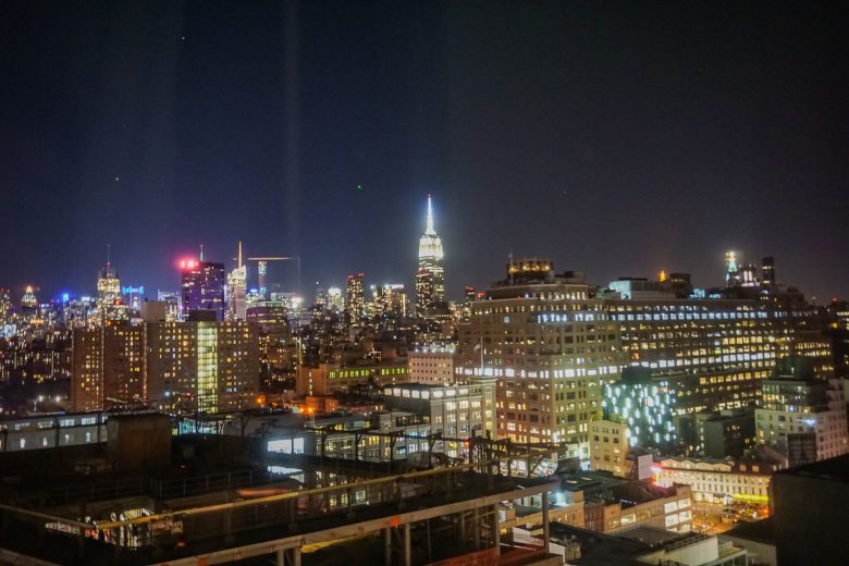 Foto da cidade de Nova York iluminada à noite, com o céu escuro ao fundo