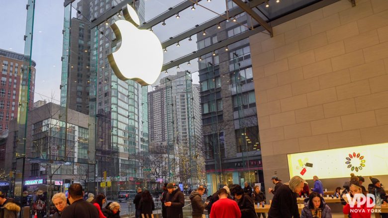 Todas as lojas são parecidas, então vale procurar uma fora da rota mais turística pra comprar iphone. Foto de uma loja da Apple em Nova York, cheia de pessoas e com a maçã que é o logo em tamanho gigante sobre o vidro