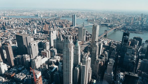 Foto da cidade de Nova York durante o da, com os edifícios altos e o céu claro ao fundo.