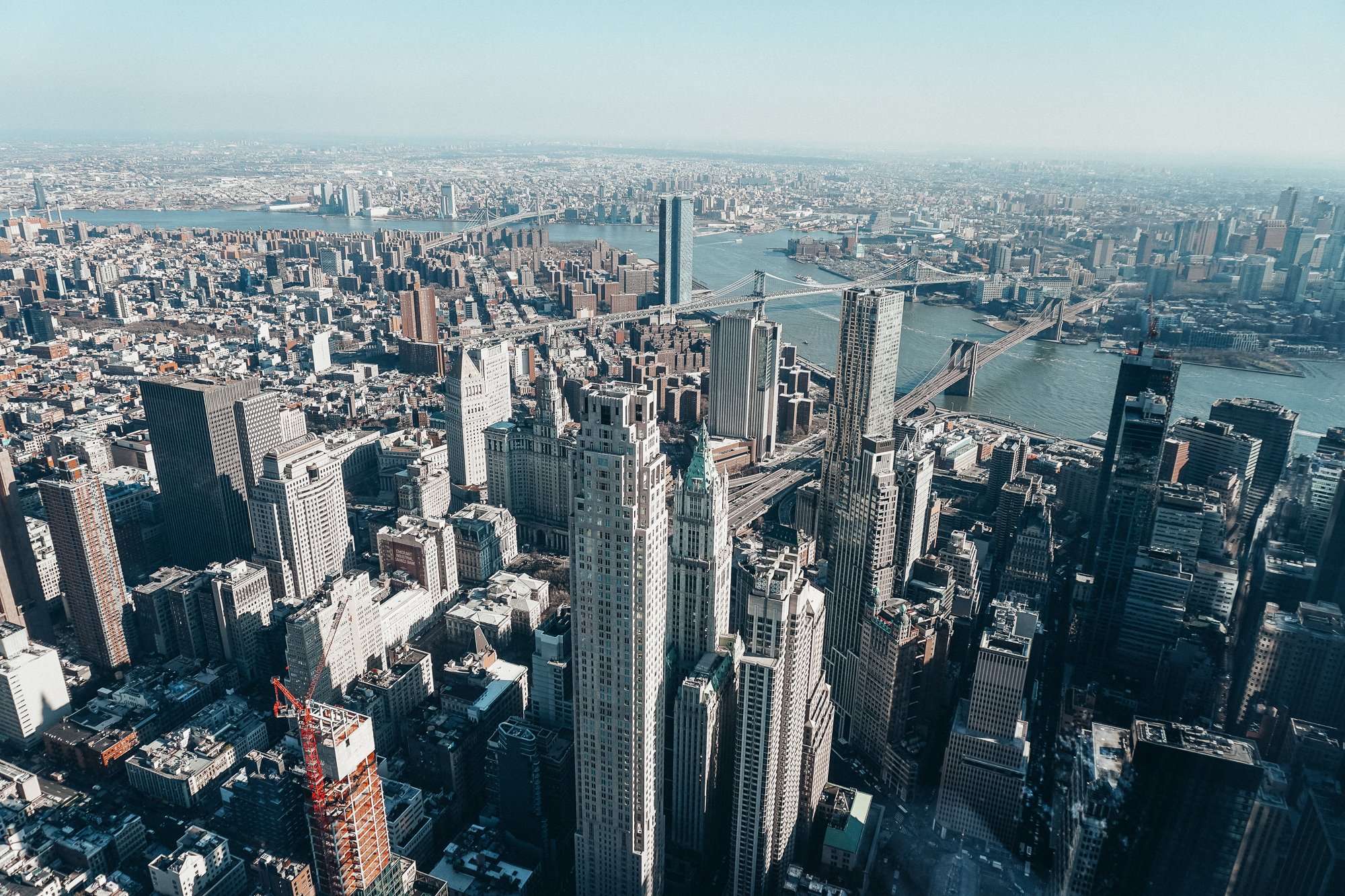 Foto da cidade de Nova York durante o da, com os edifícios altos e o céu claro ao fundo.
