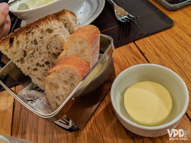 Normalmente, os pãezinhos de entrada não são cobrados nos restaurantes. Foto da cesta de pães com a manteiga ao lado 