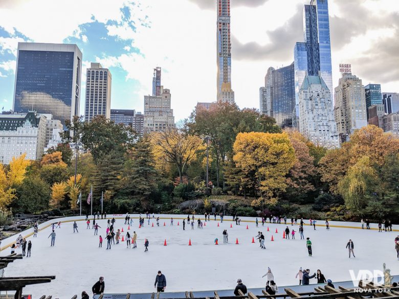 Foto do ringue de patinação do Rockefeller Center durante o dia, com árvores amareladas ao redor 