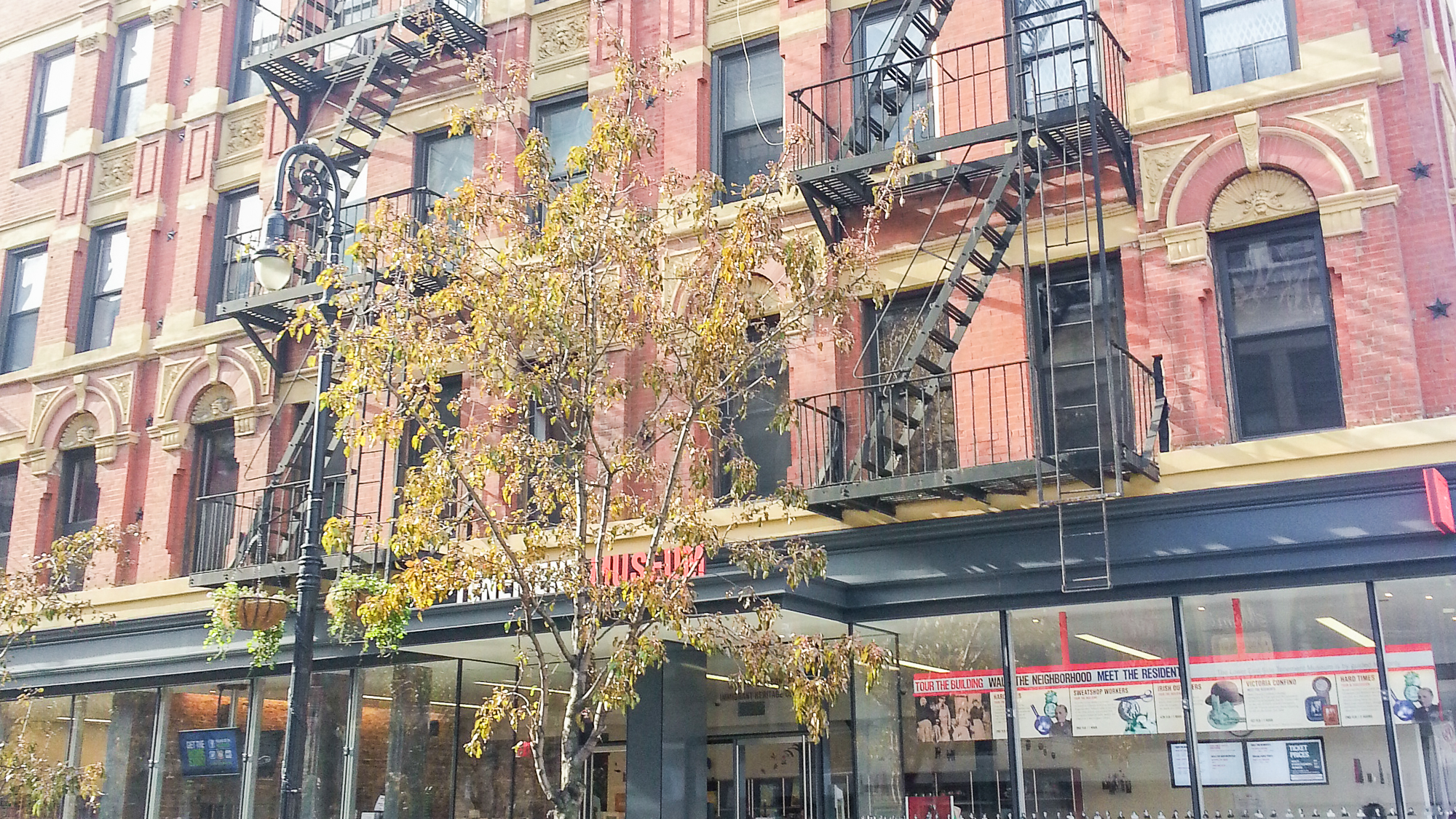 Fachada do prédio antigo onde fica o Tenement Museum em Nova York, com escadas de incêndio na frente e pintado de rosa