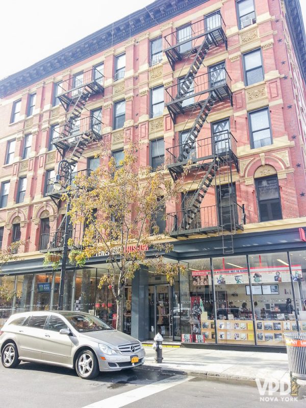 Fachada do prédio antigo onde fica o Tenement Museum em Nova York, com escadas de incêndio na frente e pintado de rosa 