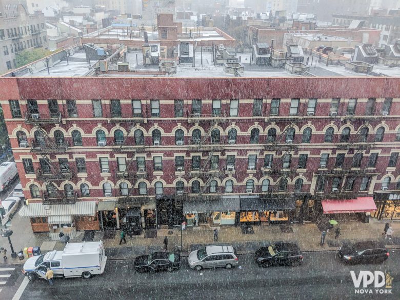 Foto de um prédio em Nova York com neve nos telhados e neve caindo do céu 