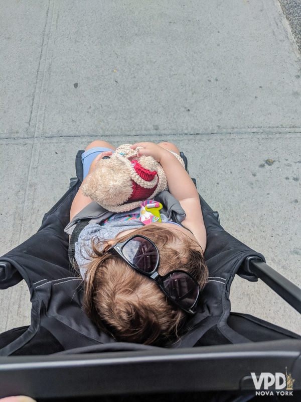 Foto da filha da Renata no carrinho, com óculos de sol na cabeça 