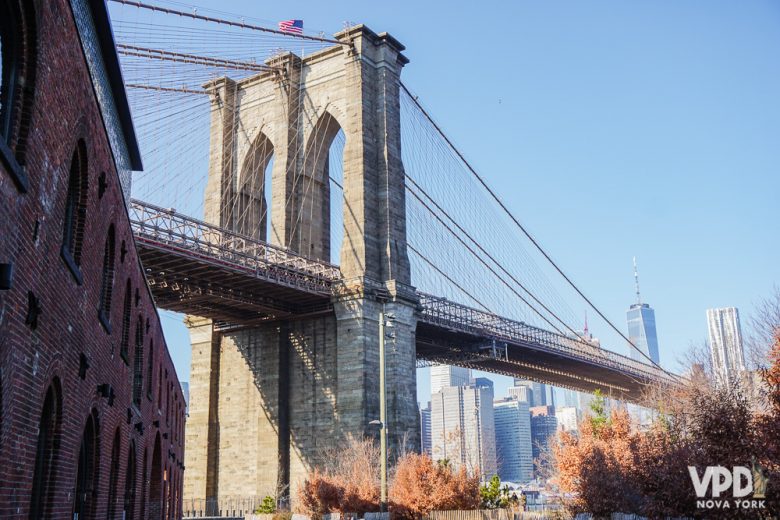 Foto da Brooklyn Bridge, uma das atrações mais fotografadas da cidade, com árvores de outono ao redor 