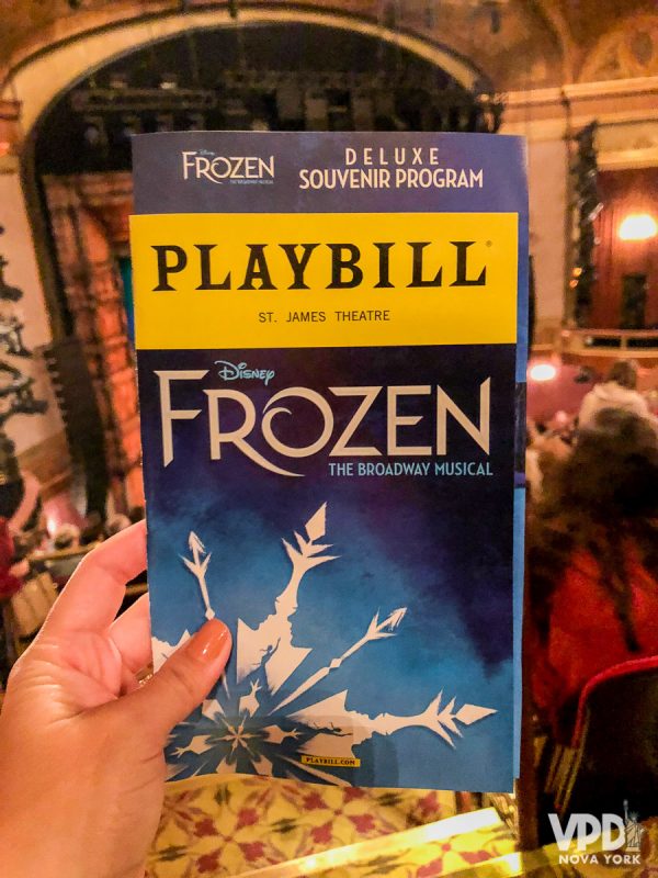 Imagem de um playbill, uma revistinha que traz informações dos musicais da Broadway. Nesse caso ele é do musical Frozen e está sendo segurado dentro do teatro. Em janeiro, a Broadway Week oferece 2 ingressos pelos preço de 1