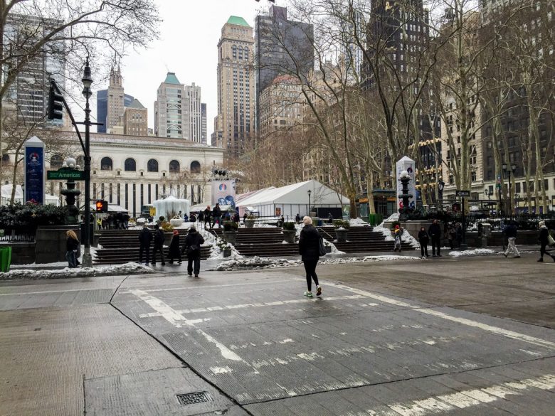 Imagem mostrando o Bryant Park em fevereiro. Ele está mais vazio, e poucas pessoas caminham na calçada. Há prédios ao fundo.