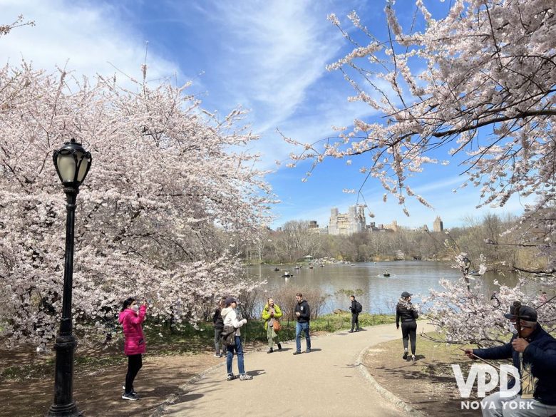 Foto da área do central park onde é possível alugar barcos. Ao fundo, dá pra ver as pessoas remando no lago, enquanto em primeiro plano há várias pessoas caminhando com roupas de inverno.